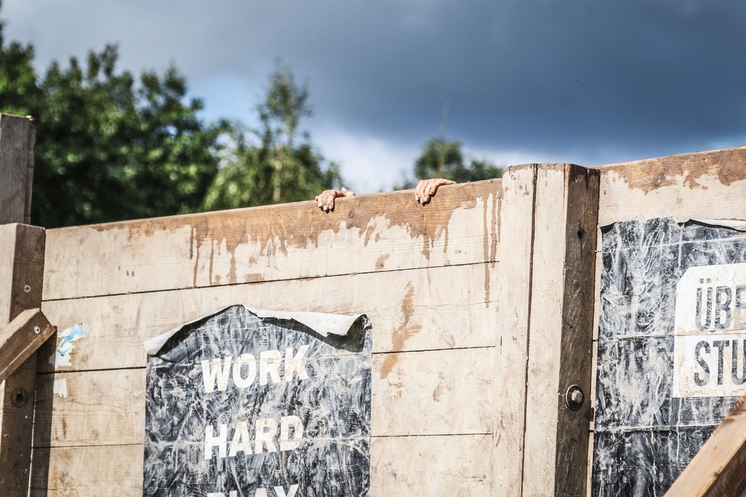 Athleten überwinden eine Holzwand